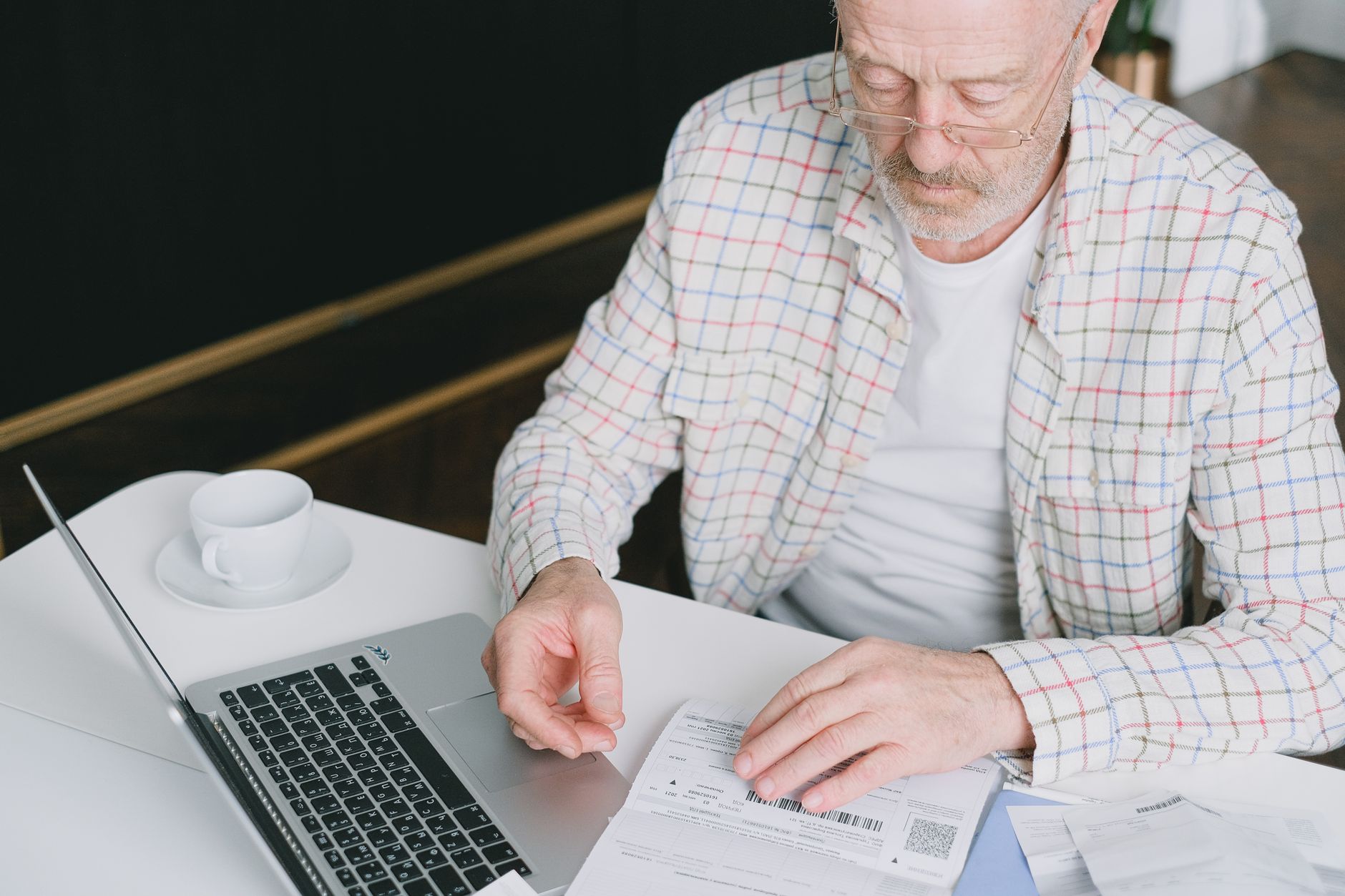 Person reading a long digital document on a laptop at a kitchen table